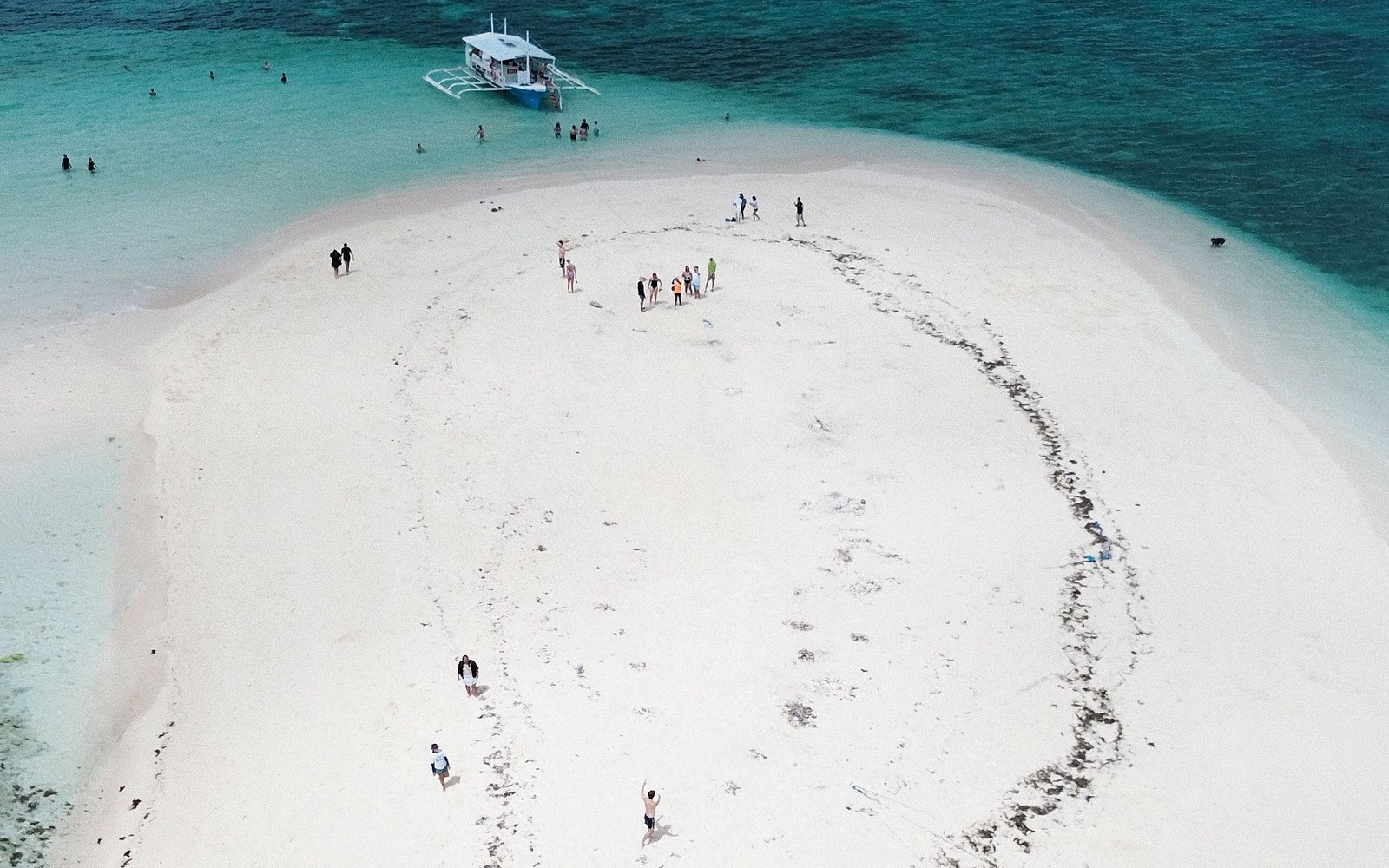Excursion boat beside a bright sandbar surrounded by turquoise water