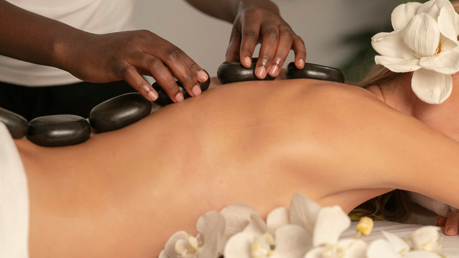Hot stone massage treatment with white flowers in a calm spa setting